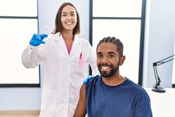 Man and woman wearing doctor uniform vaccinating at clinic