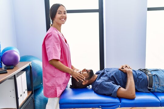 Man and woman wearing physiotherapist uniform having reiki session at physiotherpy clinic