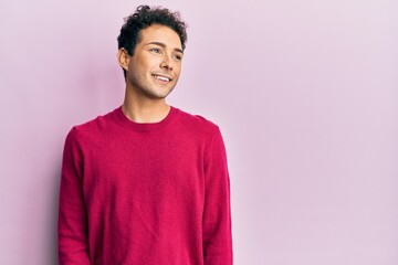Handsome hispanic man wearing casual clothes over pink background looking to side, relax profile pose with natural face and confident smile.