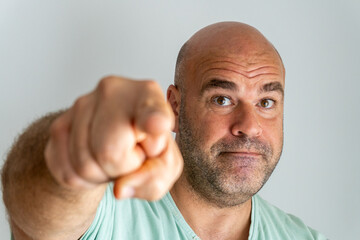Close-up of a bald, bearded, caucasian man face, gesturing and accusing with the index finger.
