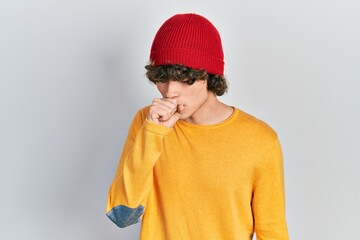 Handsome young man wearing wool hat feeling unwell and coughing as symptom for cold or bronchitis. health care concept.