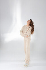 Happy model girl with afro hairstyle in a trendy sweatshirt posing with folded hands, laughing and looking up on the white background