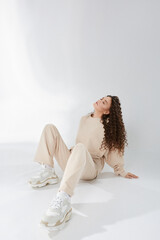 Model girl with afro hairstyle in trendy clothes and sneaker posing over white background