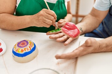 Artist couple painting palm hands at art studio.