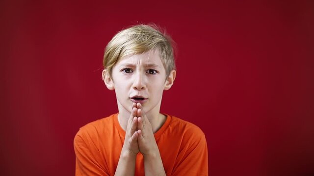 the boy put his hands together and asks Santa Claus for a gift for Christmas