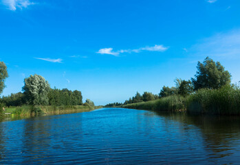 Panorama from a typical dutch water canal Kükhernster Feart between Leeuwarden and Groningen in Friesland, The Netherlands