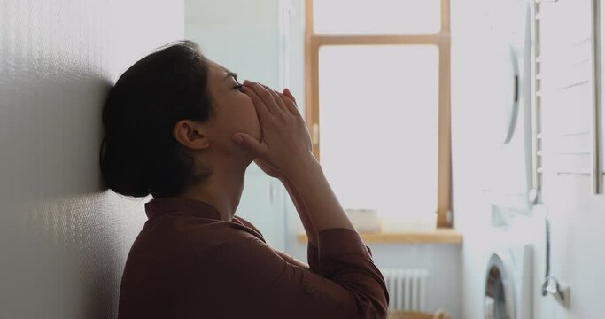 At mercy of depression. Depressed stressed Indian lady sit alone by white wall hide in laundry room think what to do. Vulnerable young woman feel bad desperate hurt cry suffer of psychological trauma