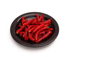 Peeled Red Chili on a black plate on a white background