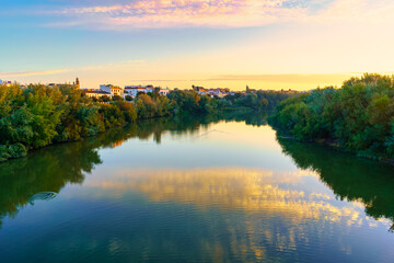 Fototapeta na wymiar Guadalquivir river at sunrise on a calm day and golden atmosphere in the city of Cordoba Spain.