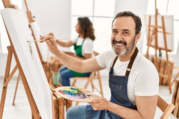 Two middle age student smiling happy painting at art studio.