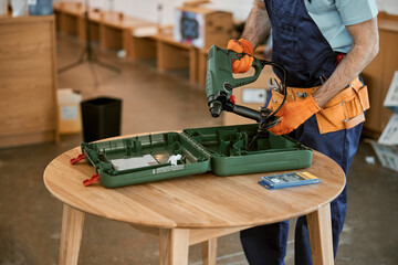 Male builder in gloves holding electric hammer drill