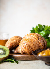 Crispy croissant with orange jam, juice and kiwi for breakfast. Tasty breakfast.