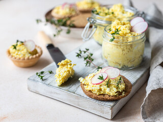 Tartlets with egg pate or salad and radish and thyme on light stone background. Egg dip in glass...