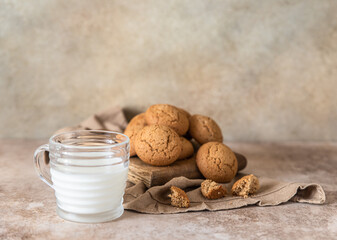 Oatmeal cookies on wooden cutting board with a cup of milk, brown concrete background. Healthy snack or dessert.