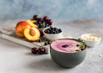 Smoothie bowl with blueberry, almond slices with fresh berries and fruit on wooden cutting board.