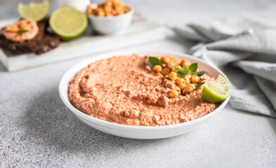 Roasted red pepper hummus garnish with mint and lime. Mashed chickpeas with red bell pepper, lime and mint. Vegetarian snack.