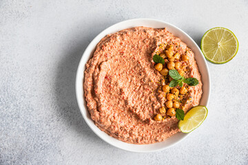 Roasted red pepper hummus garnish with mint and lime. Mashed chickpeas with red bell pepper, lime and mint. Vegetarian snack. Top view.