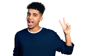 Young african american man wearing casual clothes smiling with happy face winking at the camera doing victory sign with fingers. number two.