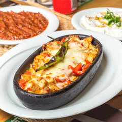 Hot meal with white cheddar and meat on a tile plate
