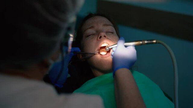 Dentist using a mouth mirror drilling machine. Doctor treating a patient in a dental clinic