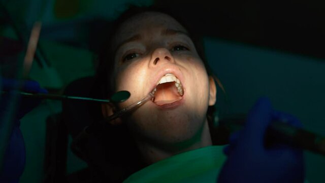 Dentist using a mouth mirror drilling machine. Doctor treating a patient in a dental clinic