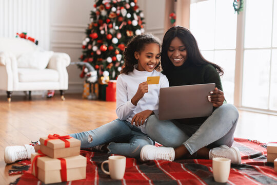 Smiling black family using pc and credit card on Xmas