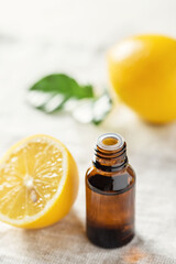 A glass bottle of lemon oil and a lemon on the table. Essential oil.