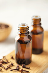 A glass bottle of clove oil and a clove on the table. Essential oil of cloves.