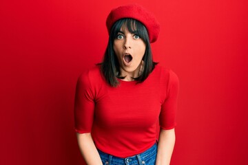 Naklejka premium Young hispanic woman wearing french look with beret afraid and shocked with surprise expression, fear and excited face.