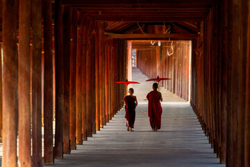 A monk holding an umbrella walks in a temple with a wooden walkway at Bagan in Myanmar on Jan 26, 2021.