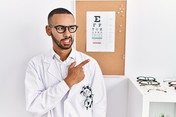 Fototapeta na wymiar African american optician man standing by eyesight test pointing aside worried and nervous with forefinger, concerned and surprised expression
