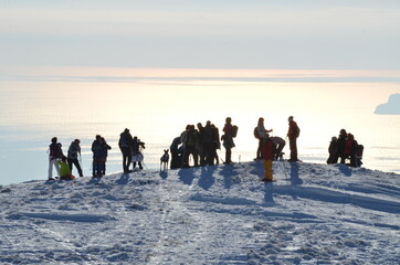 Raduno al tramonto sulla neve con sfondo il mare