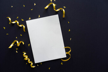 close u top view on blank white paper card with gold and silver color rolling ribbon and confetti on black background for merry christmas, happy new year festival concept © chinnarach
