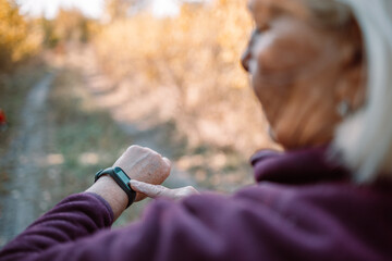 Active sport young runner checking heart rate after run outdoors in city autumn park. Healthy...