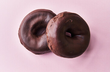  Two delicious chocolate doughnuts on a pink background