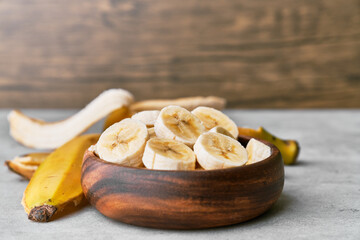Photo of banana slices in a bowl on a concrete surface