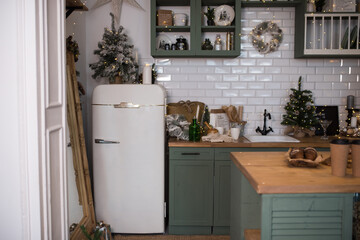 A retro-style white refrigerator in a vintage green kitchen decorated for Christmas. Kitchen...