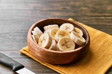 Photo of banana slices in a bowl on a wooden table