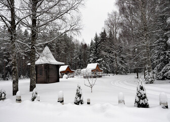 Wooden verandas stand in snowdrifts in a clearing in the middle of a snow-covered forest in winter