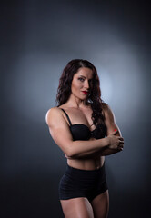 Fototapeta na wymiar Portrait of Strong fitness woman bodybuilder with black hair and tanned body.