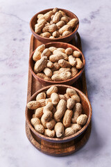  Bowls of peanuts with shell on a marble surface