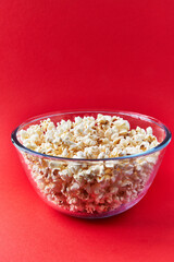  Bowl of salty popcorns on a red background