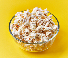 Bowl of salty popcorns on a yellow background