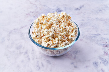  Bowl of salty popcorns on a marble surface