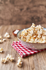  Bowl of salty popcorns on a wooden surface