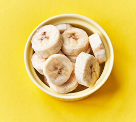  Bowl of slices of banana on a yellow background