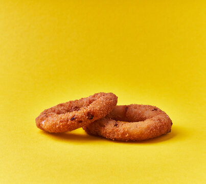  Two breaded onion rings on a yellow background