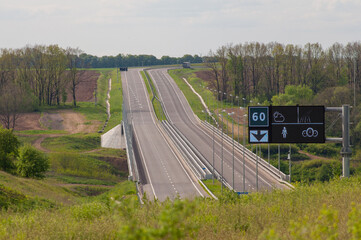 Highway with ascent and descent, bumpers and road signs.
