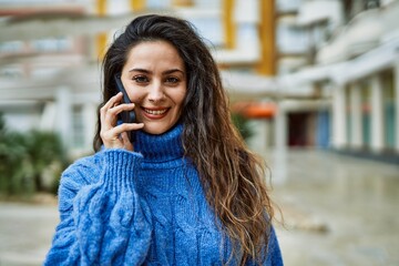 Young hispanic woman smiling happy talking on the smartphone at the city.