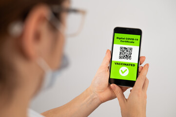 The doctor holds a smartphone with a QR code about the vaccination performed.